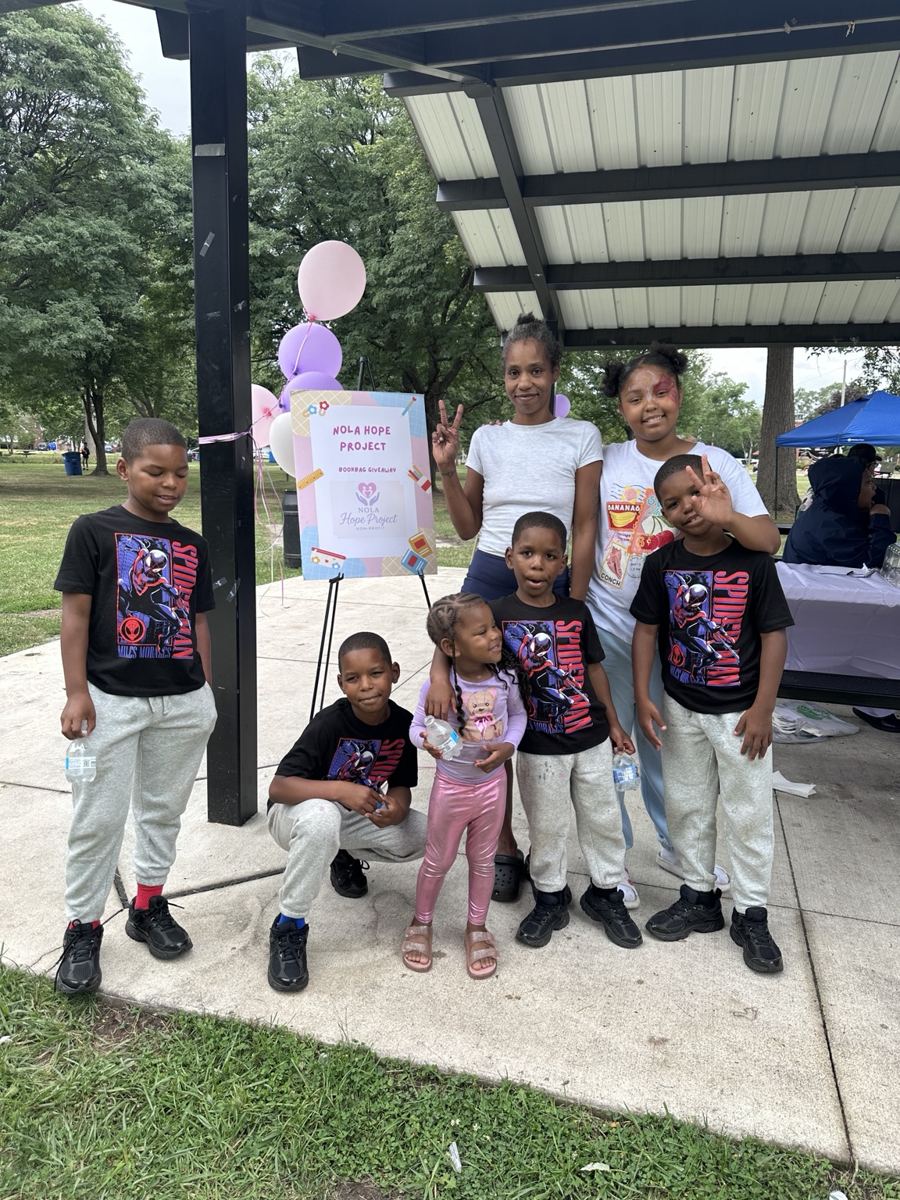 Children posing beside the Nola Hope Project event sign